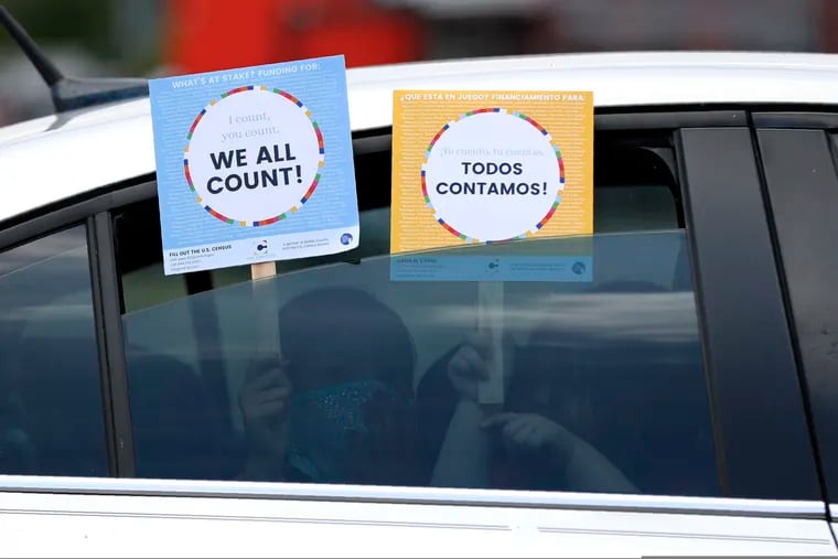 Two young children hold signs through the car window that make reference to the 2020 U.S. Census as they wait in the car with their family at an outreach event in Dallas. Thousands of census takers are about to begin the most labor-intensive part of America’s once-a-decade headcount.