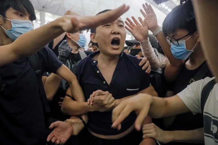 Protesters detain a man, who protesters claimed was a Chinese undercover agent during a demonstration at the Airport in Hong Kong, Tuesday, Aug. 13, 2019. Riot police clashed with pro-democracy protesters at Hong Kong's airport late Tuesday night, a chaotic end to a second day of demonstrations that caused mass flight cancellations at the Chinese city's busy transport hub.