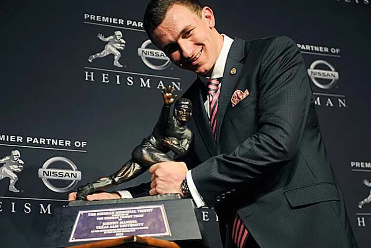 Texas A&M quarterback Johnny Manziel poses with the Heisman Trophy after becoming the first freshman to win the award. (Henny Ray Abrams/AP)