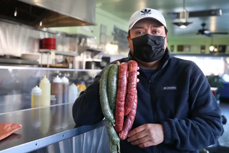 Raul Aguilar poses for a portrait while holding fresh red and green chorizo links at Sam's Morning Glory Diner in South Philadelphia on Tuesday, Jan. 12, 2021. Aguilar is a chorizo maker/butcher who lost his shop on 9th st., and then suffered from COVID-19 himself for five weeks. He is jumpstarting his business from the kitchen at Sam's Morning Glory Diner.