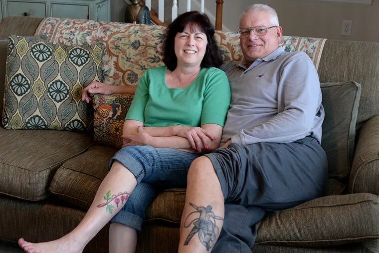 Lorraine and Peter Lukach, in their living room in Deptford, show off some of their tattoos. ( TOM GRALISH / Staff Photographer )