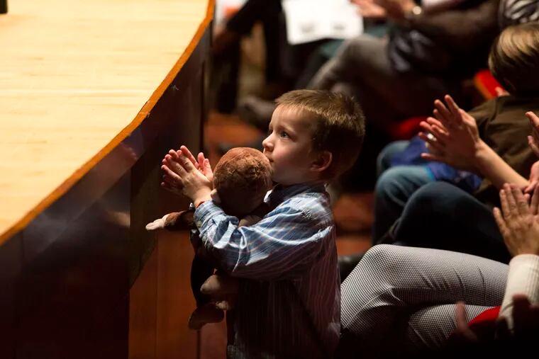 A young member of the audience claps for the Philadelphia Orchestra at its family concert. Budget cuts curtailed the production, but not the enjoyment.