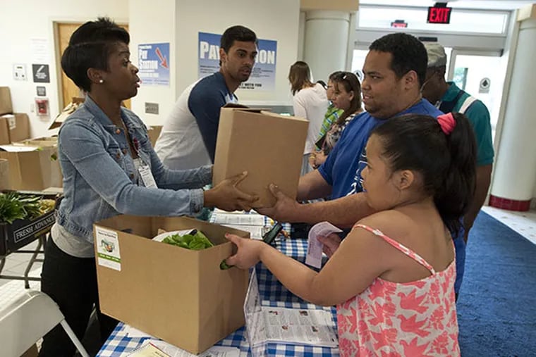 Amba Kasongo, with St. Christopher's Hospital for Children Farm to Family program, hands Lauro Melendez and his daughter Jessica, 9, a box of food after they signed up for the program at the hospital. (  RON TARVER / Staff Photographer )