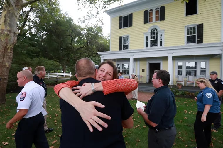 Tama Geergten hugs Willingboro firefighter Jim Anderson. The Geergtens presented $500 checks to each of the first response teams to save precious items from their home after their house nearly burned down on July 2 from a lightning strike. ( DAVID SWANSON / Staff Photographer )