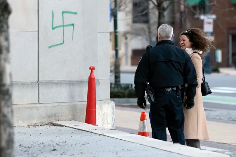 A Philadelphia police supervisor meets with Eszter Kutas, executive director of the Philadelphia Holocaust Foundation, after a green spray painted swastika was found on the wall of a building that is adjacent to the Horwitz-Wasserman Holocaust Memorial Plaza on the Ben Franklin Parkway, near North 17th Street.