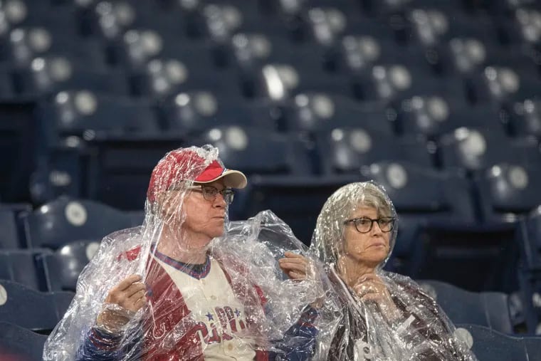 Fans shield from the rain at the Citizens Bank Park before Game 3 of baseball's World Series between the Astros and the Phillies in October.