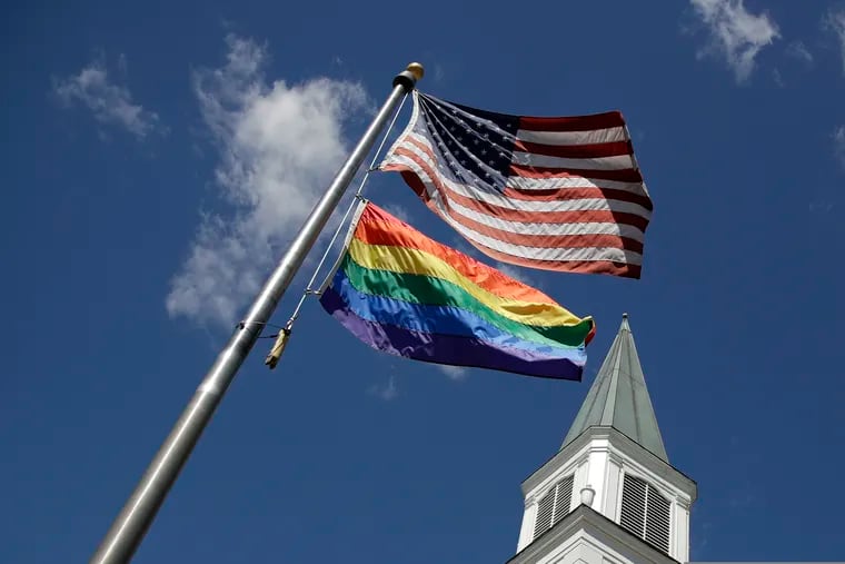A gay pride rainbow flag flies along with the U.S. flag in front of the Asbury United Methodist Church in Prairie Village, Kan., on Friday, April 19, 2019. (AP Photo/Charlie Riedel)