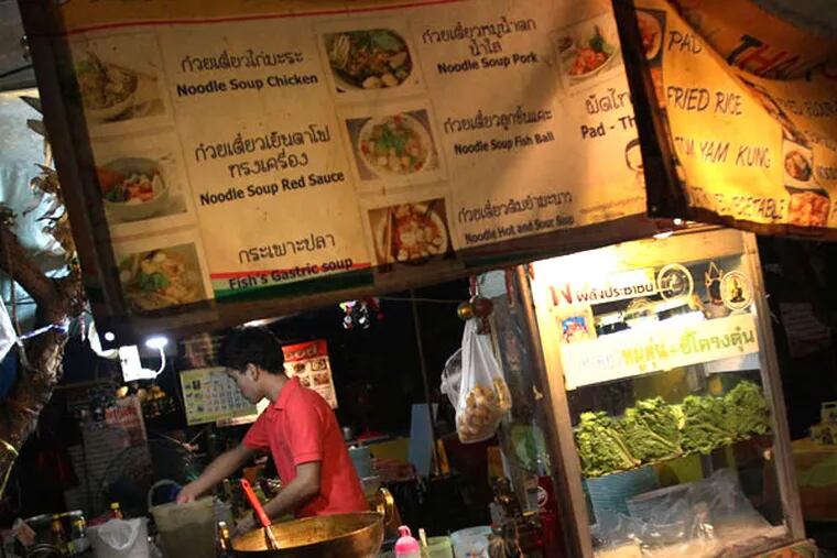 A Thai vendor cooks noodles in Bangkok. Getting sick from local water and raw fruits and vegetables can taint a trip and possibly require expensive treatment.