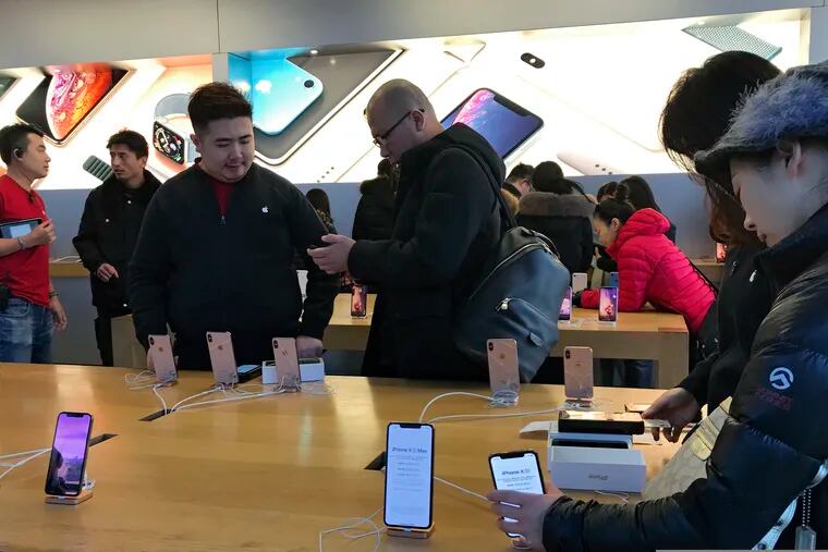 People buy latest iPhone while others try out its latest model at an Apple Store in Beijing, Tuesday, Dec. 11, 2018. China's economy czar and the U.S. Treasury secretary discussed plans for talks on a tariff battle, the government said Tuesday, indicating negotiations are going ahead despite tension over the arrest of a Chinese tech executive. (AP Photo/Andy Wong)