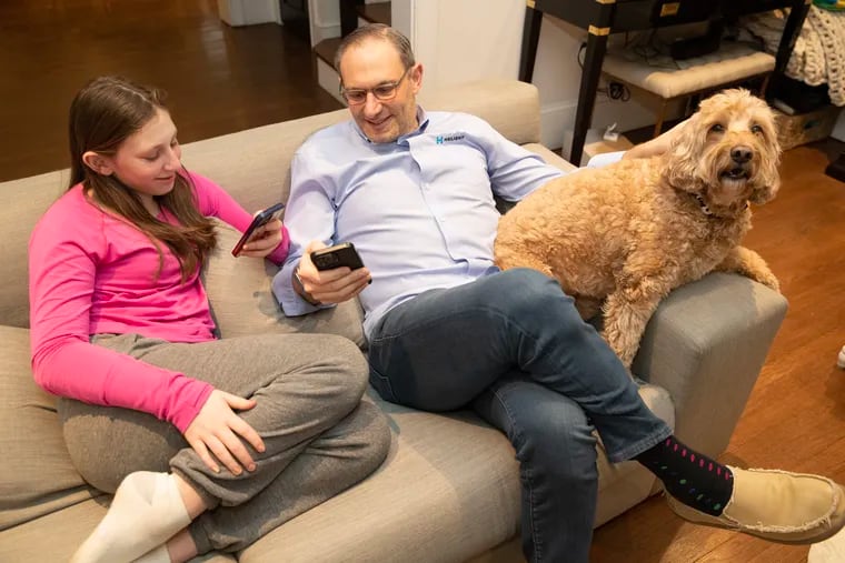 Will Fulmer, who owns an IT company, said he has had issues with cell service in and around his Bala Cynwyd home.  He got so frustrated a year ago that he drove around and mapped the cell and data coverage in the region, showing dead spots. Will and his daughter, Shira, with their dog, Max, are shown using their phones on Jan. 24, 2024.