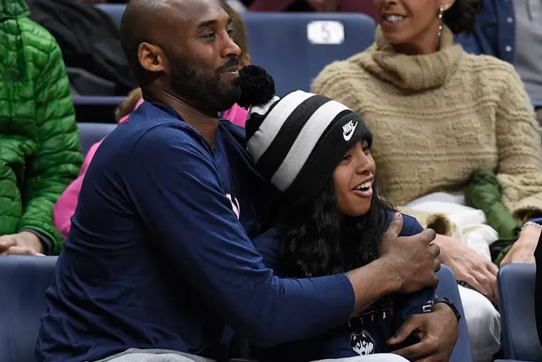 Kobe Bryant and his daughter Gianna watch the first half of an NCAA college basketball game between Connecticut and Houston in Storrs, Conn. on March 2, 2019. A public memorial service for Bryant, Gianna and seven others killed in a helicopter crash is planned for Monday, Feb. 24, 2020, at Staples Center in Los Angeles.
