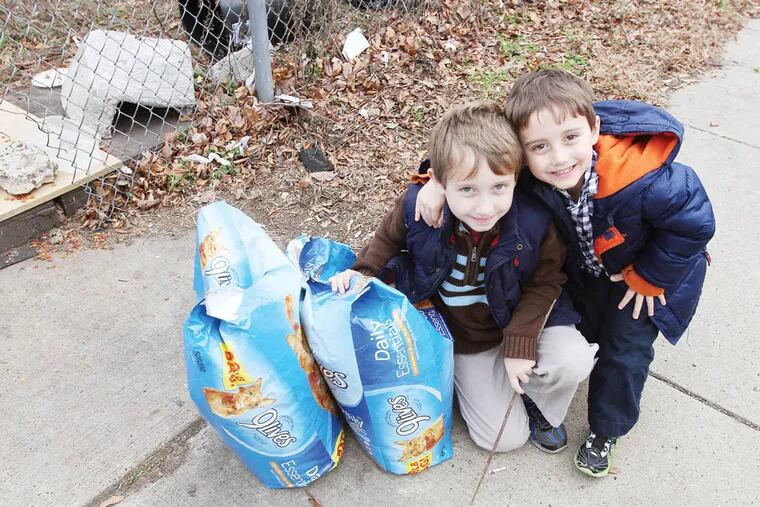 Sage Bellot, left, and his brother Lior, right, drop off food for the cats of Pier 70, where a longstanding cat colony of feral and abandoned cats live in Philadelphia on November 30, 2014. ( DAVID MAIALETTI / Staff Photographer )