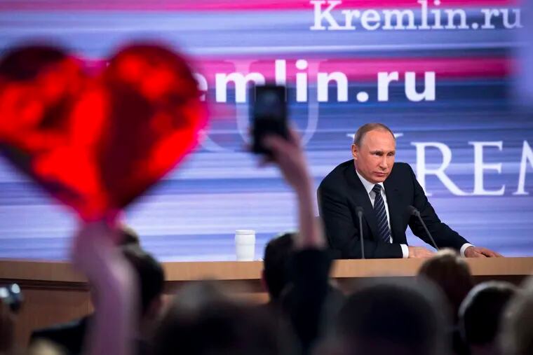 As Russia's Vladimir Putin speaks, a reporter holds up a heart-shaped poster to attract his attention.