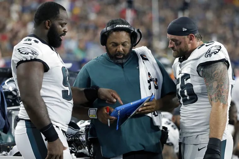 FILE – In this Aug. 16, 2018, file photo, Philadelphia Eagles defensive line coach Chris Wilson, center, confers on the sideline with defensive ends Fletcher Cox, left, and Chris Long, right, during the first half of a preseason NFL football game against the New England Patriots in Foxborough, Mass. The Eagles have so much depth on their defensive line they rotate seven players and keep them fresh for the fourth quarter. (AP Photo/Mary Schwalm, File)