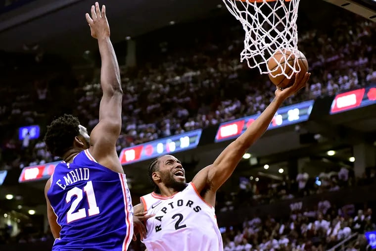 Toronto Raptors forward Kawhi Leonard (2) drives for the layup as 76ers center Joel Embiid (21) defends during the second half of Game 1 of a Eastern Conference semifinal series on Saturday.