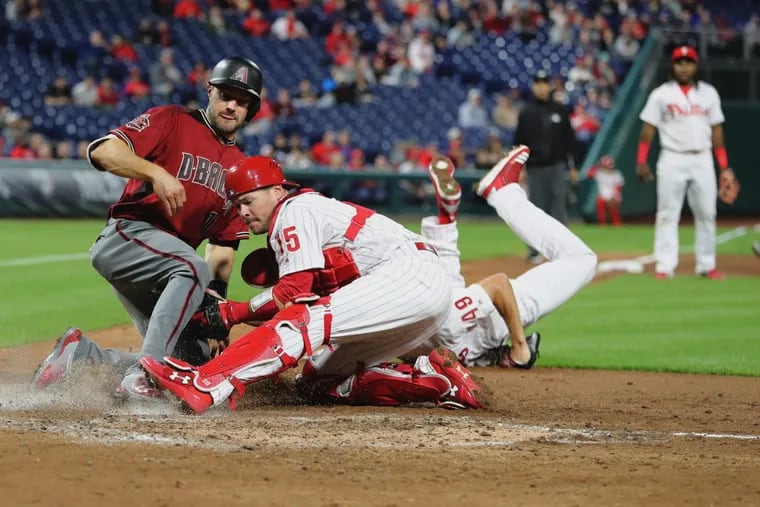 Andrew Knapp, center, of the Phillies tags out AJ Pollock of the Diamondbacks at home after Jake Arrieta, right, of the Phillies dove to flip the ball to him in the 4th inning on April 25, 2018.