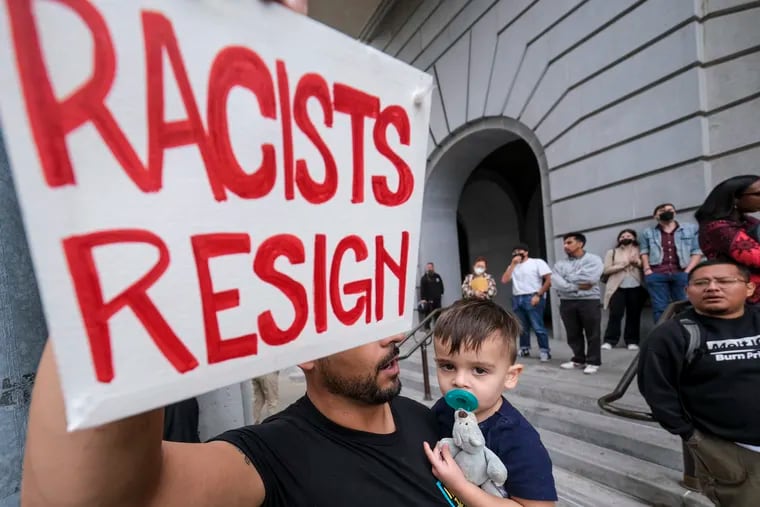 Shervin Aazami holding his son Barrett and a sign protest outside City Hall during the Los Angeles City Council meeting Tuesday, Oct. 11, 2022 in Los Angeles.