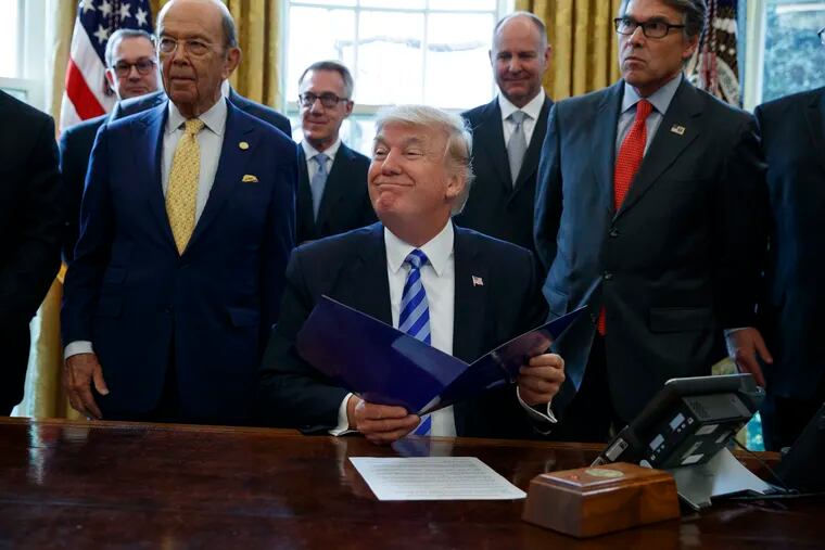 In this March 24, 2017, file photo, President Donald Trump, flanked by Commerce Secretary Wilbur Ross, left, and Energy Secretary Rick Perry, is seen in the Oval Office of the White House in Washington, during the announcing of the approval of a permit to build the Keystone XL pipeline, clearing the way for the $8 billion project. A federal judge in Montana has blocked construction of the $8 billion Keystone XL Pipeline to allow more time to study the project's potential environmental impact. U.S. District Judge Brian Morris' order on Thursday, Nov. 8, 2018, came as Calgary-based TransCanada was preparing to build the first stages of the oil pipeline in northern Montana. Environmental groups had sued TransCanada and The U.S. Department of State in federal court in Great Falls.