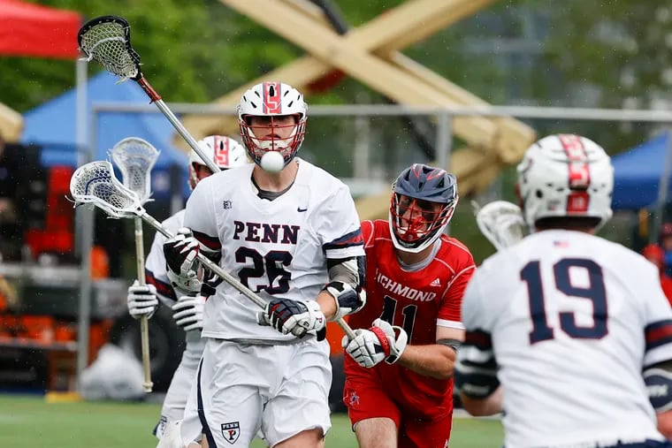 Penn's Sam Handley (left) passes the lacrosse ball to teammate Ben Bedard (right) past Richmond's Shayne Grant in the second quarter during the first round NCAA Men's Lacrosse Championship in Penn Park on Saturday, May 14, 2022.