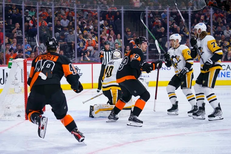 Philadelphia Flyers' Noah Cates, center, reacts to his goal on Pittsburgh Penguins goalie Louis Domingue, center left, during the second period on Sunday, April 24, 2022, in Philadelphia.