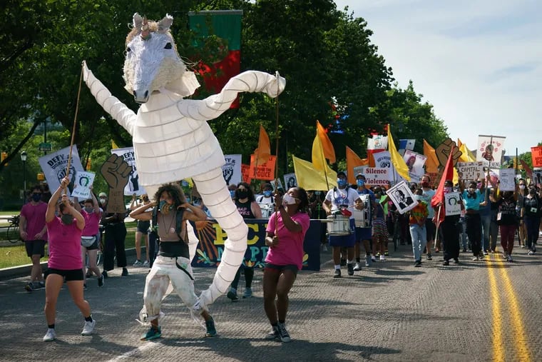 Samantha Rise, program director at Girls Rock Philly (at the base of a unicorn puppet), marches on the Benjamin Franklin Parkway during an arts event organized by the Artist Coalition for a Just Philadelphia on June 16.