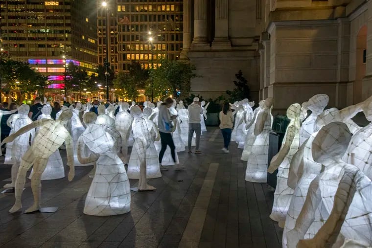 Visitors attending an interfaith prayer and art exhibit in Dilworth Park at City Hall on Thursday. The Irish Diaspora Center hosted the event to raise awareness for mental health. The exhibit is of more than 100 human-size lanterns that community members made in workshops with an Irish artist. They each represent a person struggling with mental health issues or someone lost to suicide.