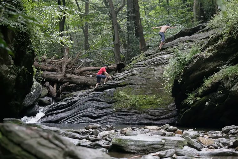 People climb up the rocks to the trail after police informed folks that swimming was not allowed in Devils Pool in the Wissahickon Valley Park in Phila., Pa. on Aug. 18, 2018. Officers were very friendly and explained that they could stay in the park but that there is a $100 fine for swimming there. ELIZABETH ROBERTSON / Staff Photographer