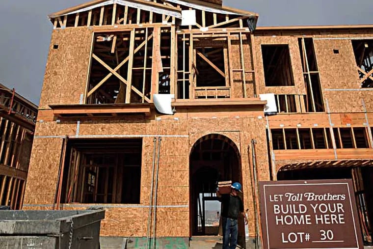 FILE photo shows Toll Brothers Inc. signage displayed at a construction site as a contractor carries scaffolding for a new home at the Baker Ranch development in Lake Forest, California, U.S. (Patrick T. Fallon/Bloomberg)
