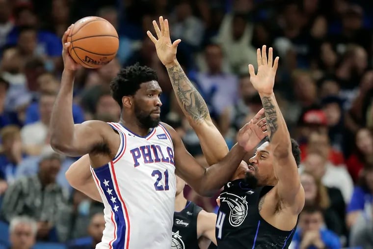 The 76ers' Joel Embiid passes the ball around Orlando's Khem Birch during a game last month. The two squads could meet in the first round of the playoffs.