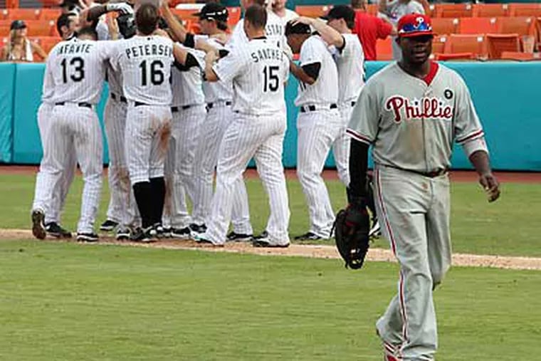 Ryan Howard walks off the field as the Marlins celebrate after winning in the 14th inning. (Hector Gabino/AP)