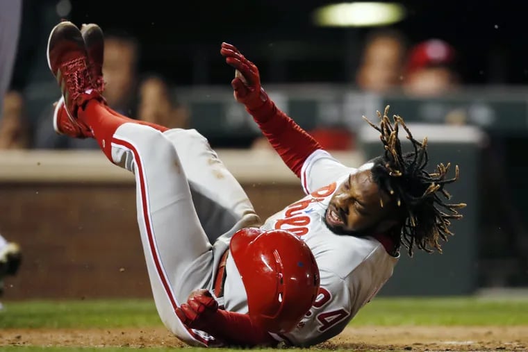 Phillies' outfielder Roman Quinn stumbles after being tagged out at home plate while trying to score on a single hit by Dylan Cozens against the Colorado Rockies on Wednesday.