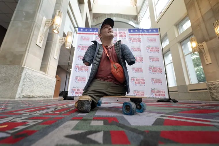 Chris Koch picked up his racing bib at the Convention Center on Friday so he can compete in Sunday's Philadelphia Marathon, propelling himself on his longboard.
