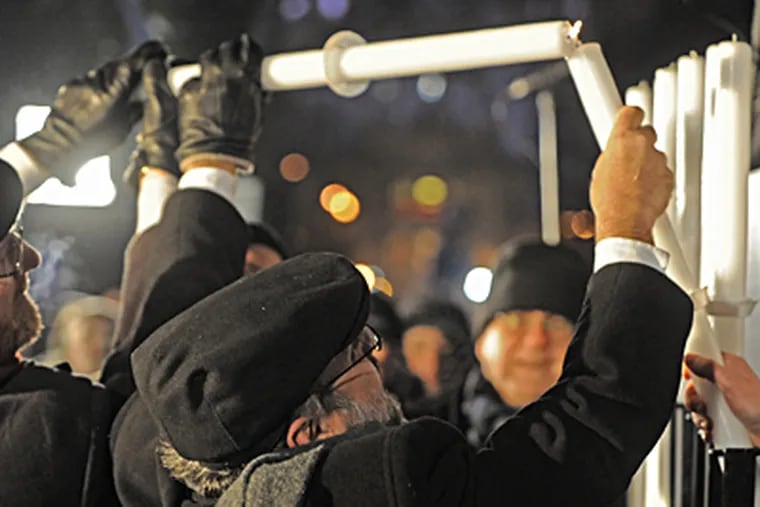 Poland's chief rabbi Michael Schudrich lights the first candle celebrating the beginning of Hanukkah, the Jewish festival of lights, on Grzybowski Square in Warsaw, Poland, on Saturday. ALIK KEPLICZ / Associated Press