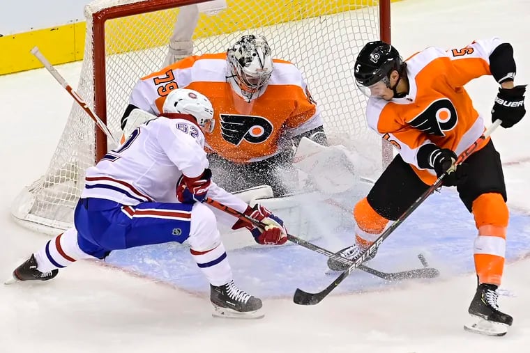 Flyers goaltender Carter Hart makes a save on Montreal's Artturi Lehkonen (left) as Phil Myers defends in Game 1 of the Eastern Conference quarterfinals.