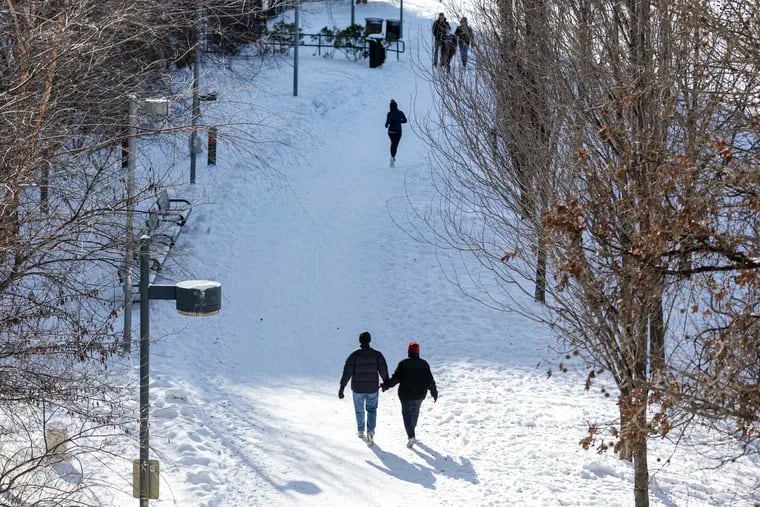 A couple walking along the Schuylkill River trail a day after the the most recent snowfall in Philly.