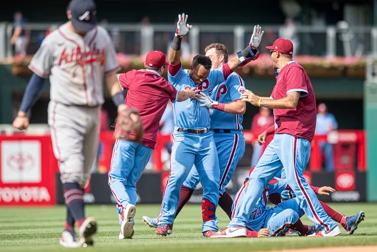 The Phillies celebrate after Jean Segura (center) hit a game-winning two-run double off Braves pitcher Chris Martin in the 10th inning Thursday.