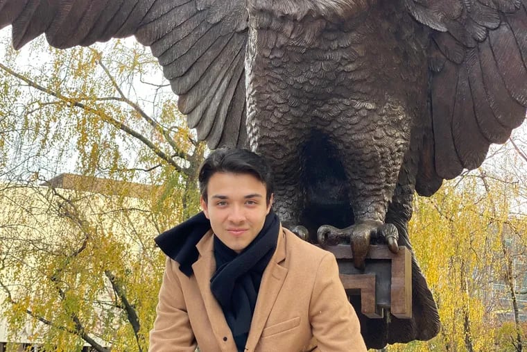 Victor Guillen, who fled Venezuela amid strife, poses with the Temple University owl in November as he begins graduate school.