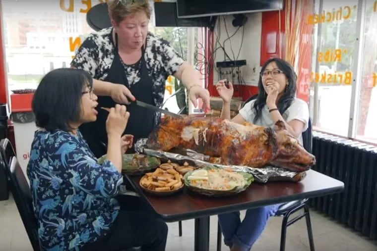 Lalaine Balan carves the lechon at her restaurant, Philippine Smoked BBQ and Grill, in Wilmington, Delaware, for Francesca Manto and her mother, Vikki.