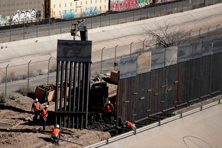 Workers place sections of metal wall as a new barrier is built along the Texas-Mexico border near downtown El Paso, Texas, last month.