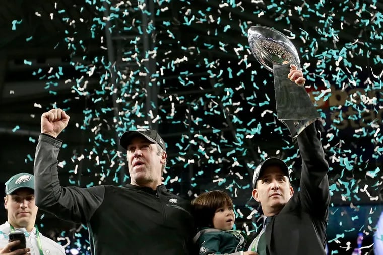 Eagles head coach Doug Pederson pumps his fist as top executive Howie Roseman holds up the Lombardi trophy in Minnesota on Feb. 4.
