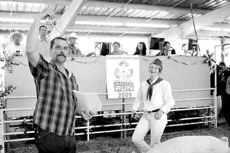 An auctioneer, Lawrence Bettincourt , signals to a buyer as Kayla Weststeyn, 14, gets $10 per pound for her Yorkshire hog at the fair in Turlock, Calif.