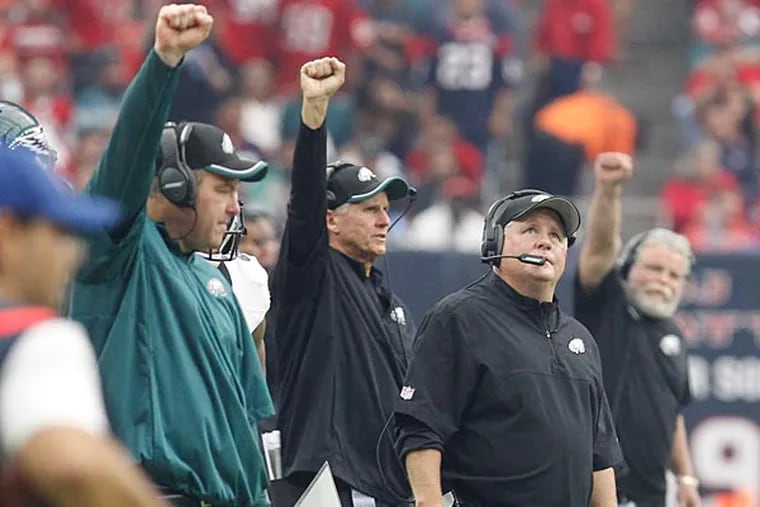 Coaches give signals as head coach Chip Kelly watches a replay. (Ron Cortes/Staff Photographer)