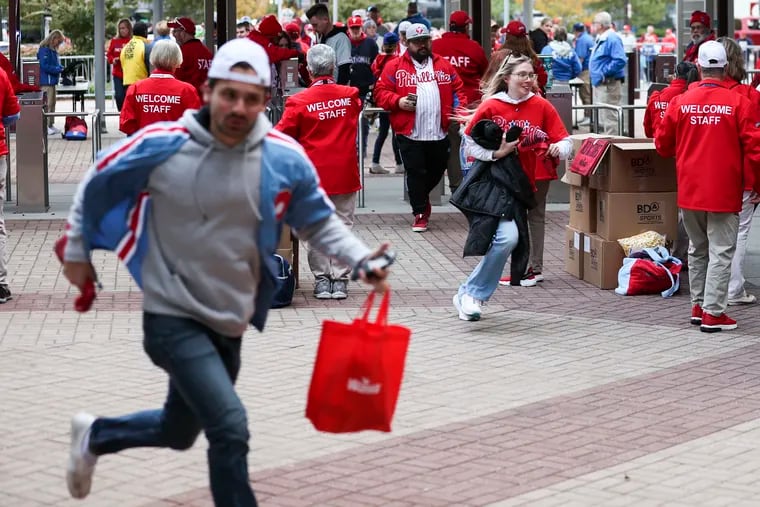 Phillies fans rush the gates before Game 2 of the NLCS against the Diamondbacks. Bags like the one this fan in the foreground is carrying won't be permitted inside Citizens Bank Park this year.