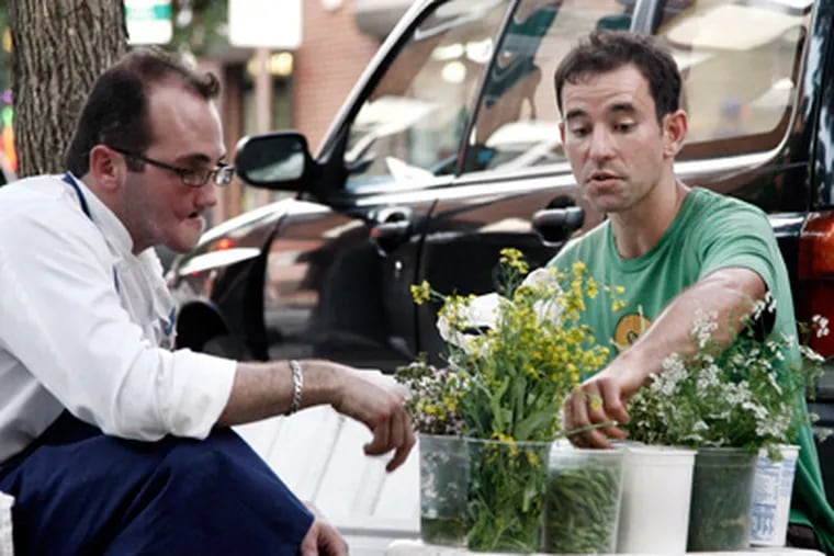David Siller (right) shows a radish seed pod to Christopher Kearse, chef de cuisine at Pumpkin on South Street. (Elizabeth Robertson / Staff Photographer)