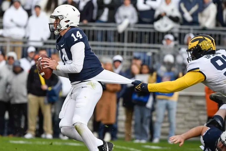 Penn State quarterback Sean Clifford looks to escape a tackle attempt by Michigan defensive end Taylor Upshaw  in the first quarter Saturday.