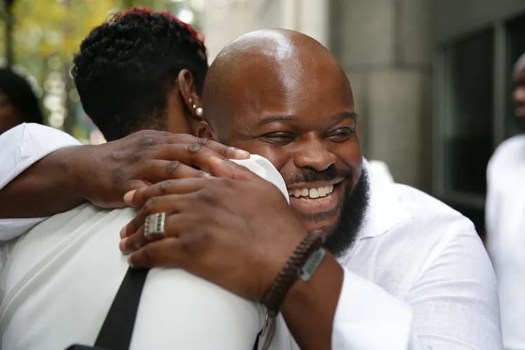 Jimmy Dennis, right, hugs the sister of a man whose murder conviction was also overturned, outside the Criminal Justice Center on October 1, 2019.