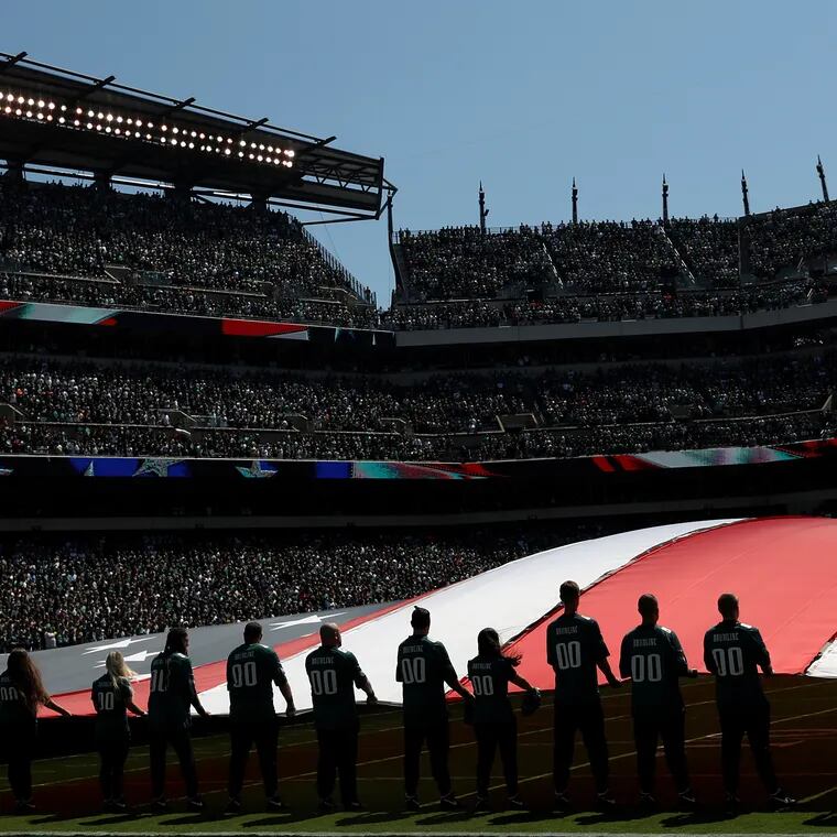Volunteers hold the American flag during the national anthem before a 2019 Eagles game.