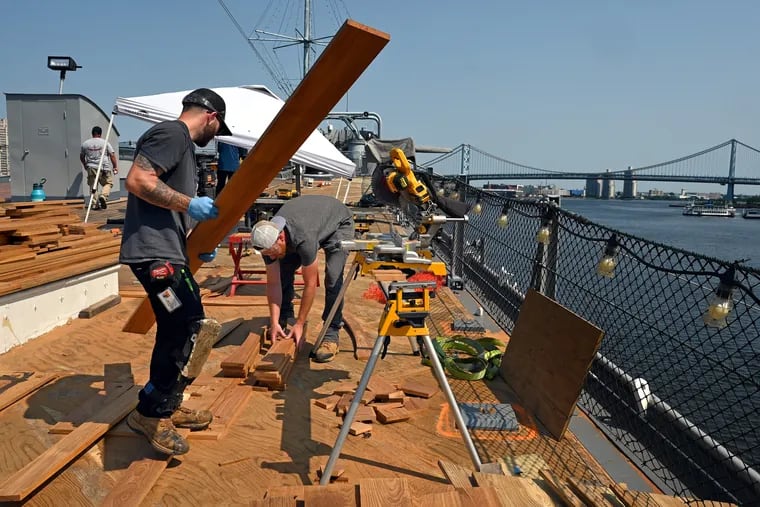 Carpenter John Henry (left) and painter Mike Fitzmaurice (right) are members of the crew replacing the teak deck of the Battleship New Jersey. The $4  million project is due to be finished by year's end.