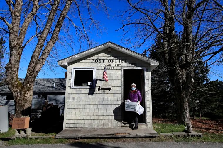 Postmistress Donna DeWitt carries mail at the tiny post office on Isle Au Haut, Maine. The post office serves the 70 or so year-round island residents.