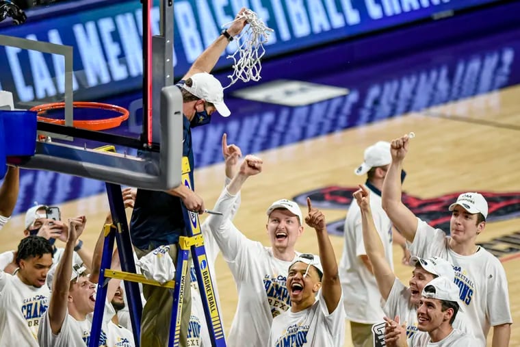 Drexel coach Zach Spiker holds up the net as he celebrates with the team after a win over Elon in the Colonial Athletic Association championship game.